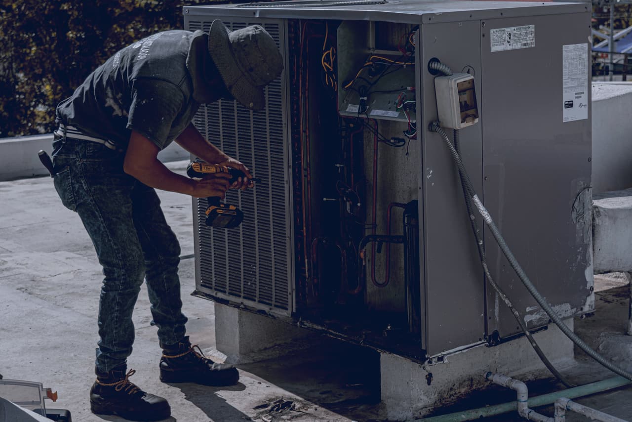HVAC technician working on an outdoor unit on a flat roof